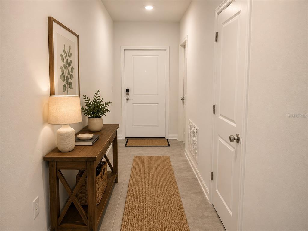 A bright entryway features a wooden console table, a runner rug, and a white door — 5782 LE MARIN WAY, KISSIMMEE, FL