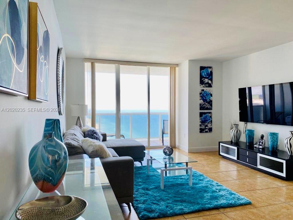 A living room features a blue rug, a glass coffee table, and ocean views — 1830 S Ocean Dr # 4810, Hallandale Beach FL 33009, HALLANDALE BEACH, FL
