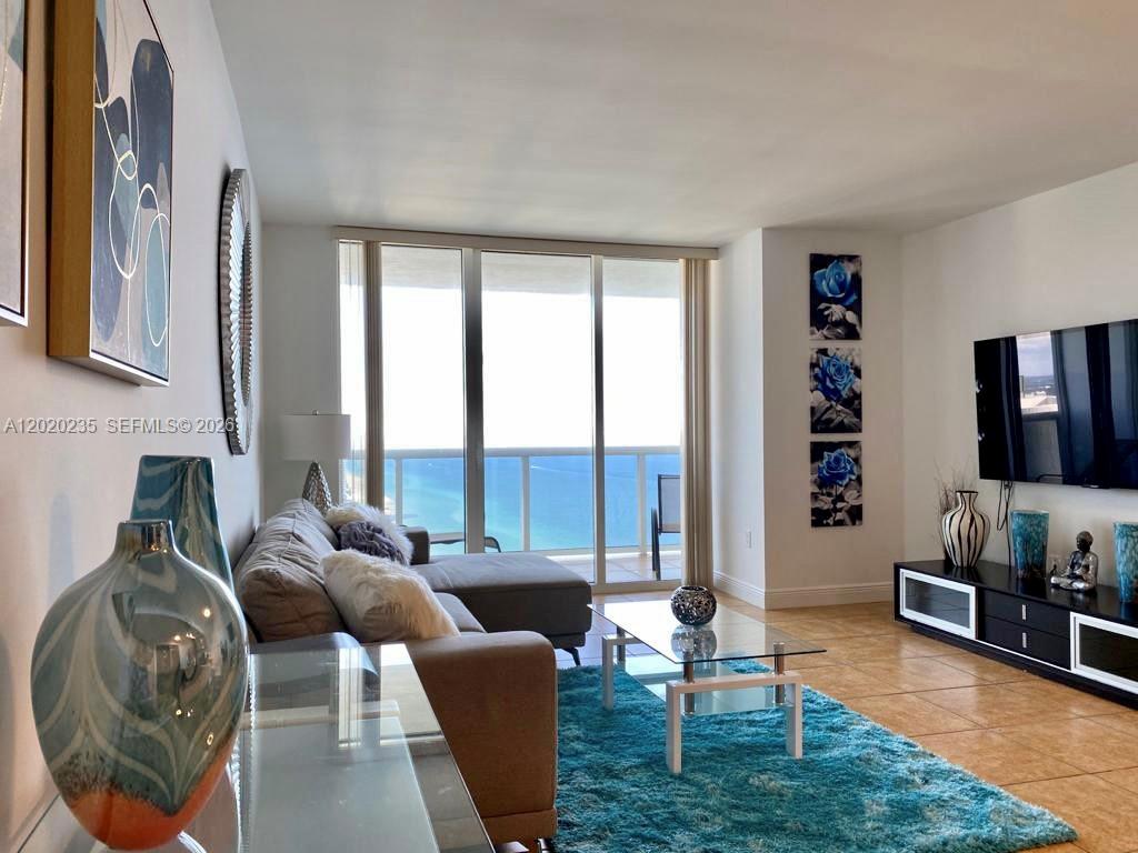 A living room features a sectional sofa, a glass coffee table, and ocean views — 1830 S Ocean Dr # 4810, Hallandale Beach FL 33009, HALLANDALE BEACH, FL