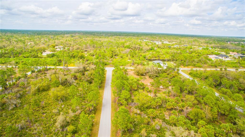 An aerial view shows a paved road intersecting through a wooded, undeveloped residential area — 2284 PATRICK STREET, PORT CHARLOTTE, FL