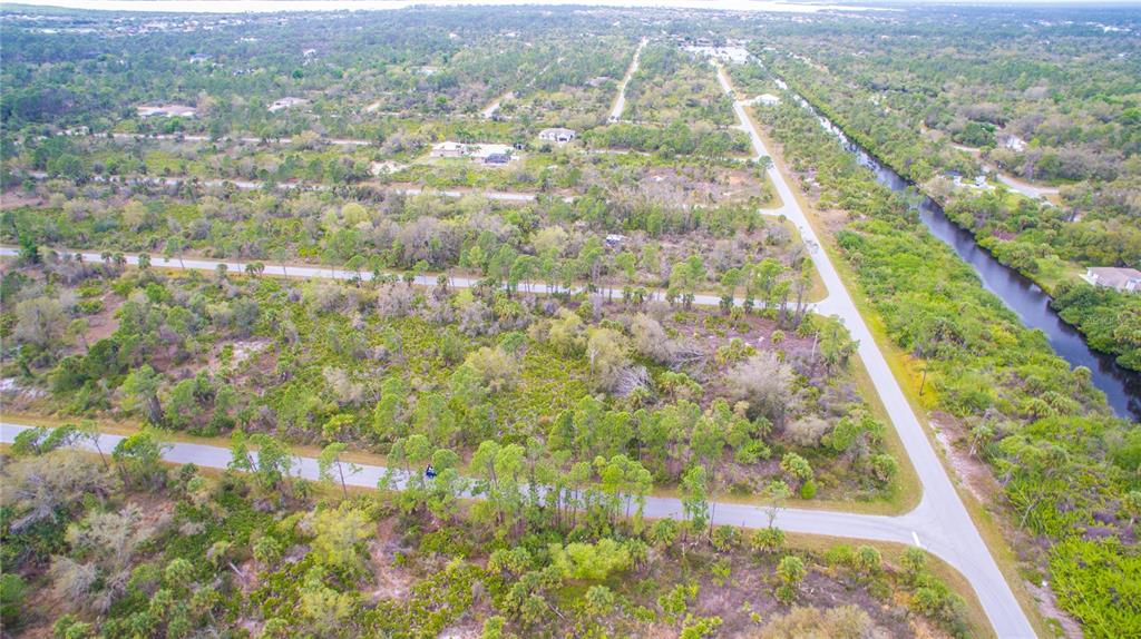 An aerial view shows a residential area with paved roads, undeveloped lots, and a canal — 2284 PATRICK STREET, PORT CHARLOTTE, FL