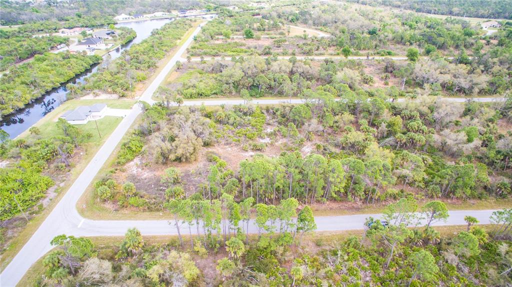 An aerial view shows a vacant, wooded residential lot situated between two paved roads — 2284 PATRICK STREET, PORT CHARLOTTE, FL