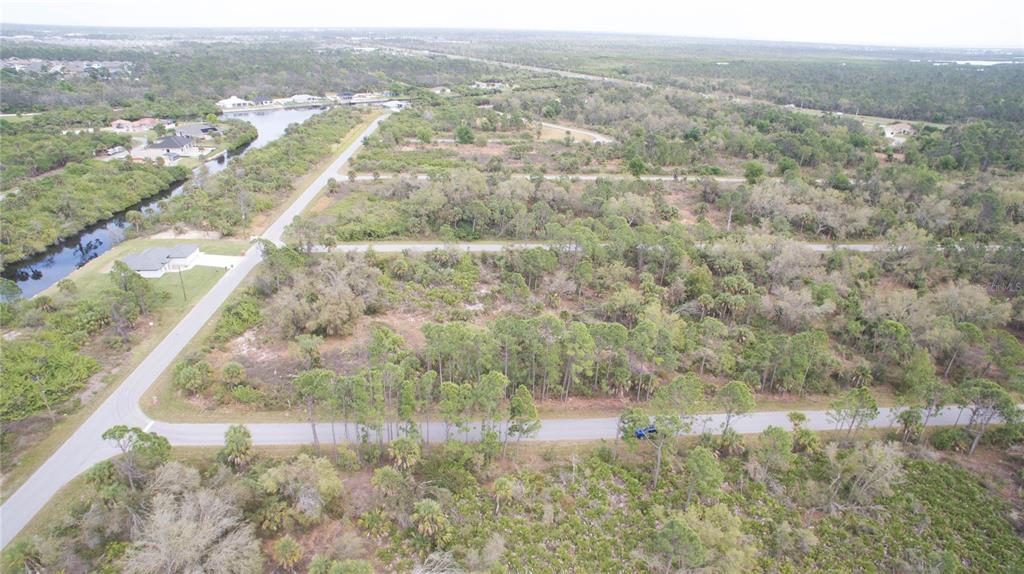 An aerial view shows a paved road winding through a wooded area with scattered residential lots — 2284 PATRICK STREET, PORT CHARLOTTE, FL