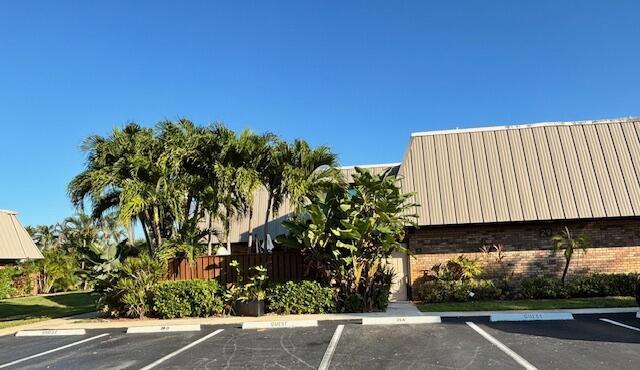 A low-rise building with a brown metal roof sits behind a parking lot and landscaping — 1420 Ocean Way # 29a, Jupiter FL 33477, JUPITER, FL