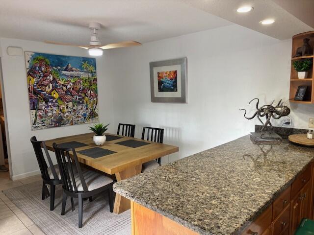 A dining area with a wooden table and chairs sits next to a granite-topped kitchen island — 1420 Ocean Way # 29a, Jupiter FL 33477, JUPITER, FL