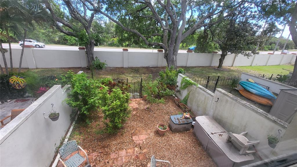 An elevated view of a small, fenced-in backyard with gravel, potted plants, and two kayaks — 2700 BAYSHORE BOULEVARD UNIT 592, DUNEDIN, FL