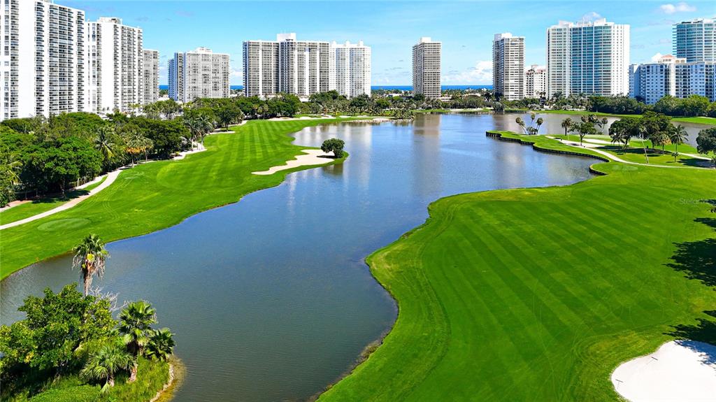 An aerial view of a golf course with a large pond and surrounding high-rise buildings — 20225 NE 34TH COURT UNIT 817, MIAMI, FL