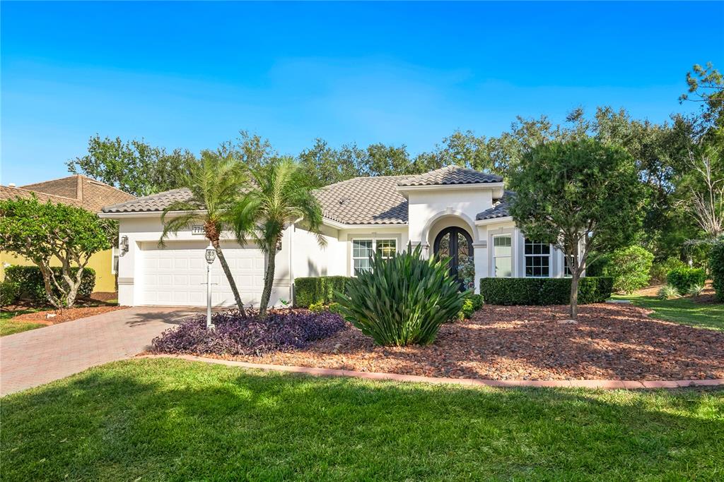 A single-story house with a white stucco exterior, tile roof, and a paved driveway — 7719 LATROBE COURT, LAKEWOOD RANCH, FL