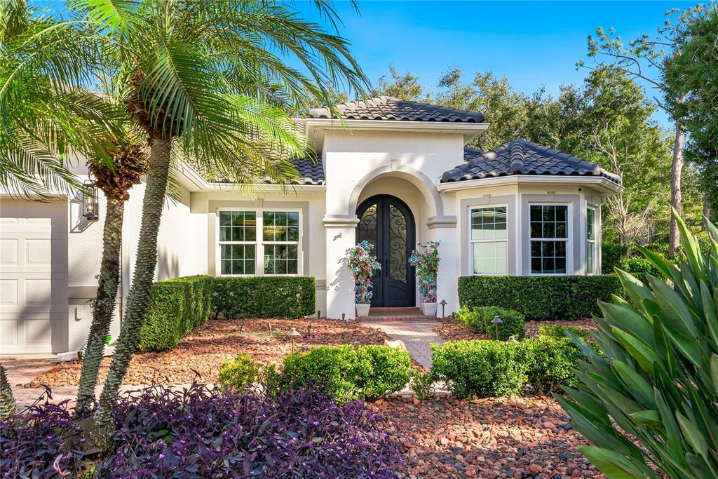The exterior of a single-story stucco home features a tiled roof, arched entryway, and landscaping — 7719 LATROBE COURT, LAKEWOOD RANCH, FL