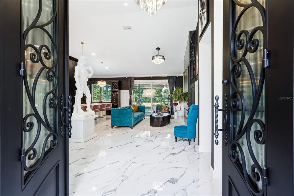 A view through double doors into a living room with marble floors and a statue — 7719 LATROBE COURT, LAKEWOOD RANCH, FL