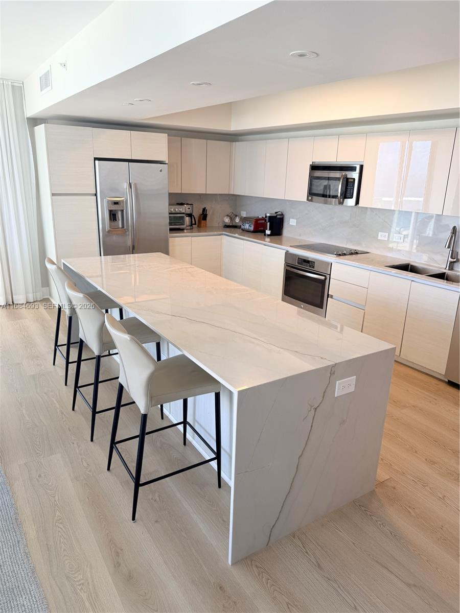 A modern kitchen features light wood cabinetry, a large marble-topped island, and stainless steel appliances — 2600 E Hallandale Beach blvd # T2701, Hallandale Beach FL 33009, HALLANDALE BEACH, FL