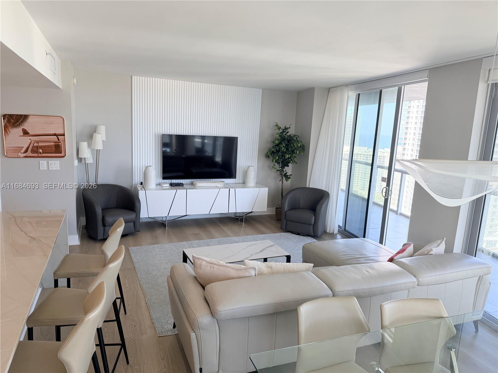 A modern living room features a white media console, a sectional sofa, and floor-to-ceiling windows — 2600 E Hallandale Beach blvd # T2701, Hallandale Beach FL 33009, HALLANDALE BEACH, FL