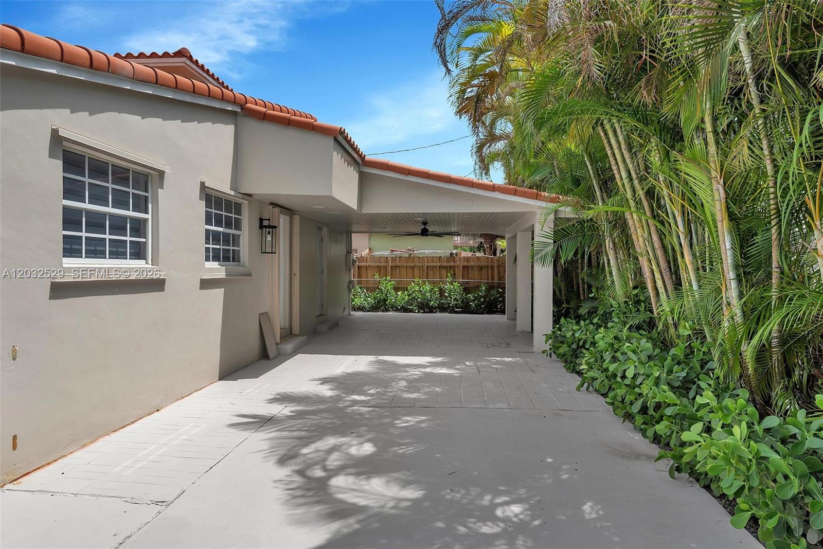 A paved driveway leads to a covered carport beside a house with a tiled roof — 424 W 13th St, Hialeah FL 33010, HIALEAH, FL