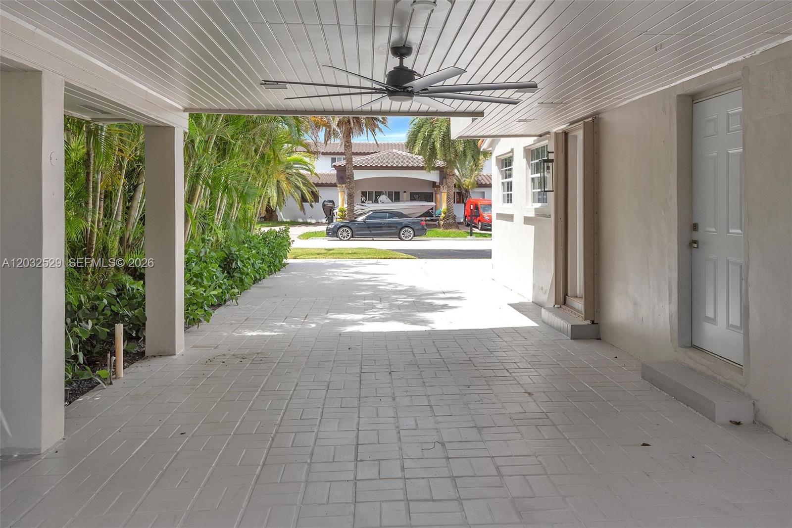 A covered outdoor patio features a ceiling fan, paved flooring, and a white door — 424 W 13th St, Hialeah FL 33010, HIALEAH, FL