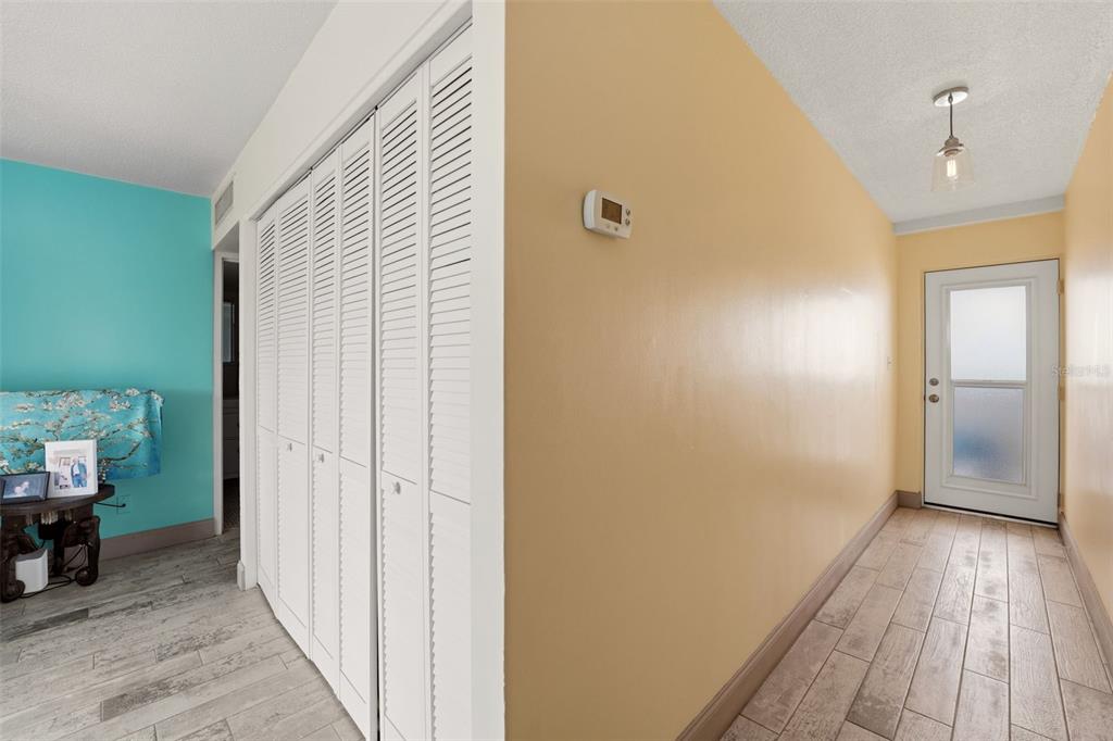 A hallway with light-colored wood-look tile flooring, white louvered closet doors, and yellow walls — 33 S GULFSTREAM AVENUE UNIT 404, SARASOTA, FL