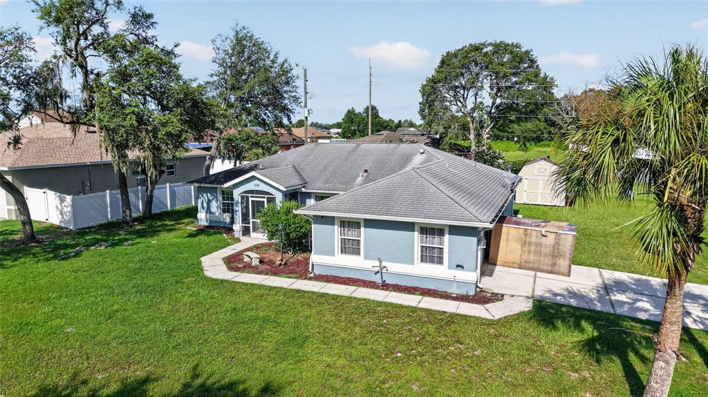 An aerial view shows a blue single-story house with a gray roof and a shed — 304 MARION OAKS COURSE, OCALA, FL