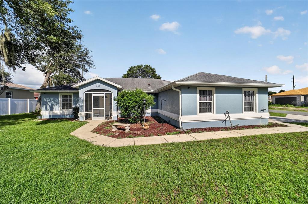 A blue single-story house with a screened front porch and a concrete walkway — 304 MARION OAKS COURSE, OCALA, FL