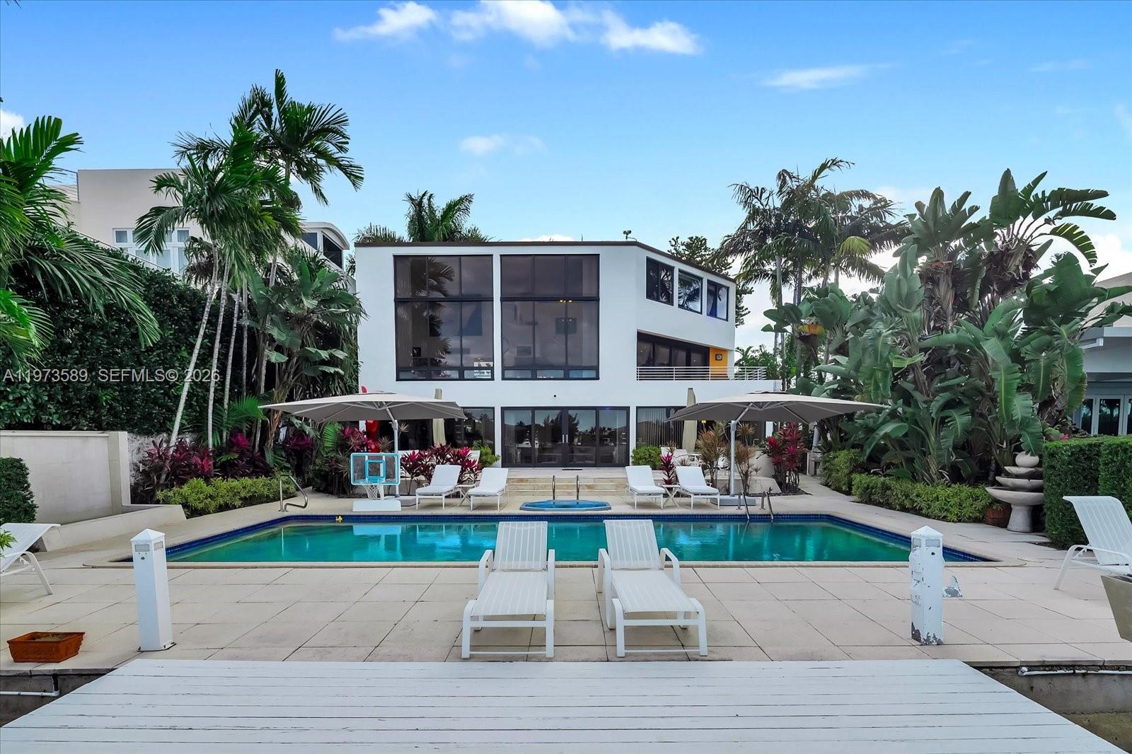 A modern white house features a swimming pool, lounge chairs, and palm trees in back — 279 N Hibiscus Dr # 0, Miami Beach FL 33139, MIAMI BEACH, FL