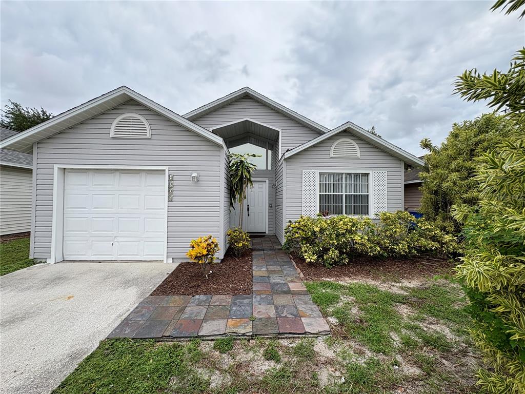A single-story house with gray siding, a garage, and a tiled walkway leading to the entrance — 4007 39TH STREET W, BRADENTON, FL