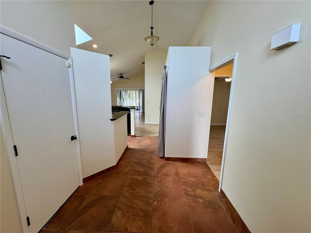 A tiled hallway leads toward a kitchen and living area with vaulted ceilings — 4007 39TH STREET W, BRADENTON, FL