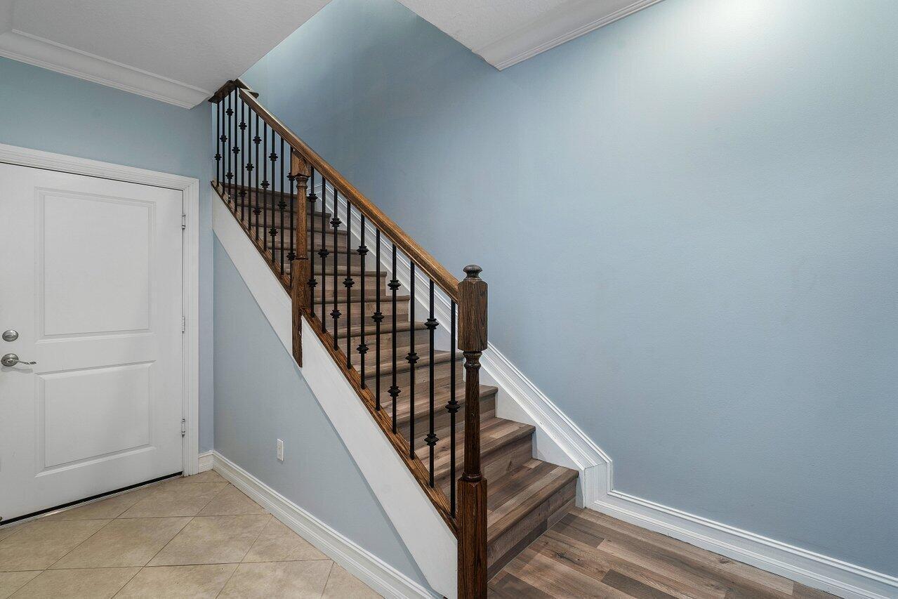A staircase with wood treads and a black metal railing sits beside a white door — 224 S Federal Highway # 4, FL 33460, FL