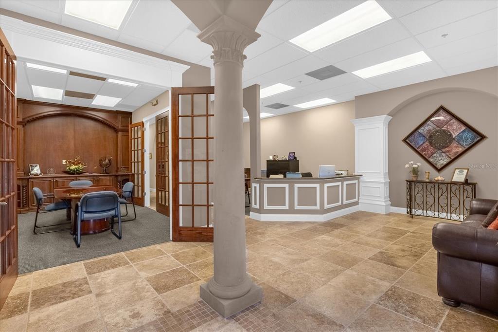 An office interior features a reception desk, a conference area with wood paneling, and tile flooring — 1507 PARK CENTER DRIVE UNIT F, ORLANDO, FL