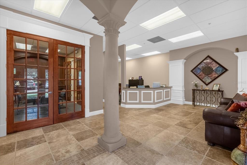 A reception area features a central column, tile flooring, a wooden door, and a front desk — 1507 PARK CENTER DRIVE UNIT F, ORLANDO, FL