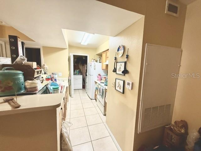 A kitchen features tiled floors, white appliances, and a pass-through counter overlooking the space — 3012 PARKWAY BOULEVARD UNIT 106, KISSIMMEE, FL