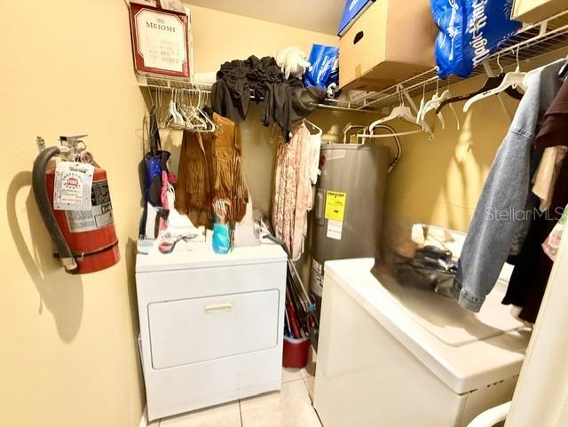 A laundry closet contains a white dryer, a water heater, and hanging clothes — 3012 PARKWAY BOULEVARD UNIT 106, KISSIMMEE, FL