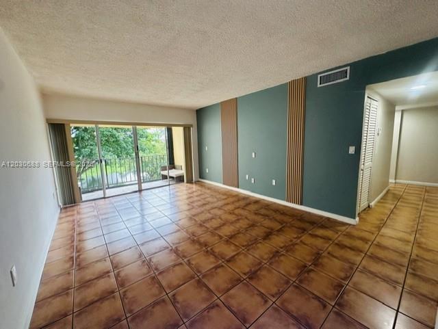A living room features brown tile flooring, a teal accent wall, and a sliding glass door — 8775 Park Blvd # 309, Miami FL 33172, MIAMI, FL
