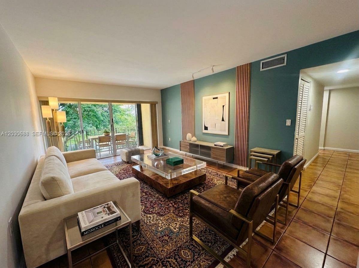 A living room features a teal accent wall, wood slats, a patterned rug, and balcony access — 8775 Park Blvd # 309, Miami FL 33172, MIAMI, FL