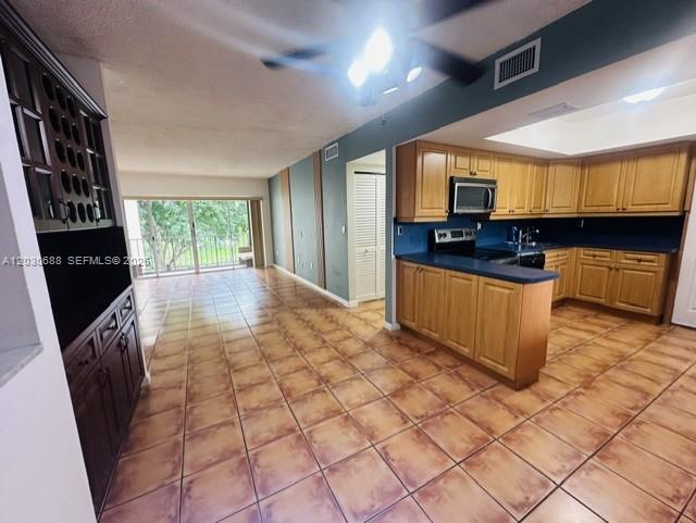 A kitchen with light wood cabinets and tile flooring opens into a living area — 8775 Park Blvd # 309, Miami FL 33172, MIAMI, FL