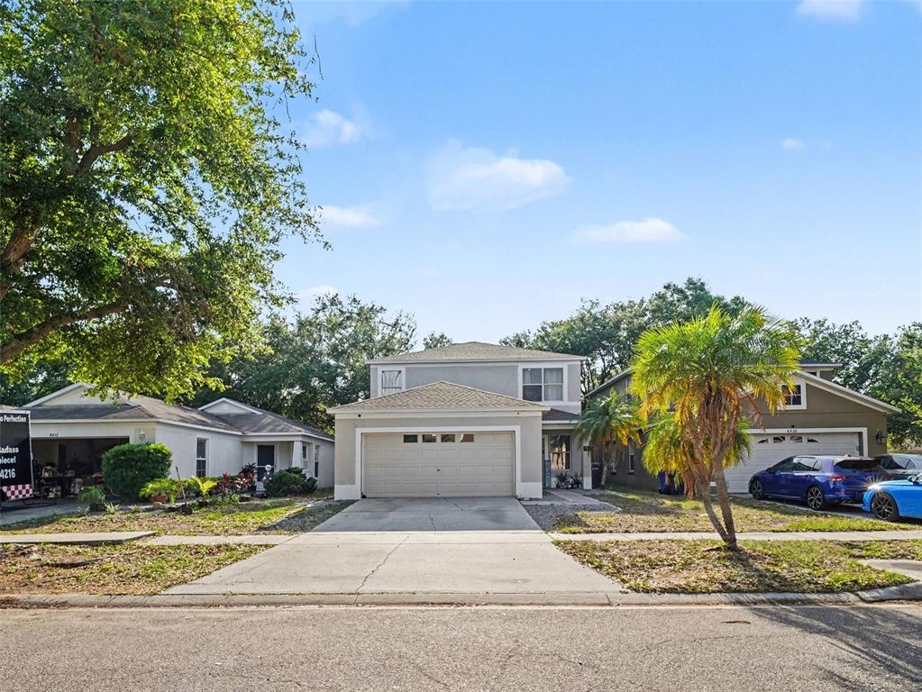 A two-story house with a beige exterior, a two-car garage, and a concrete driveway — 8430 QUARTER HORSE DRIVE, RIVERVIEW, FL