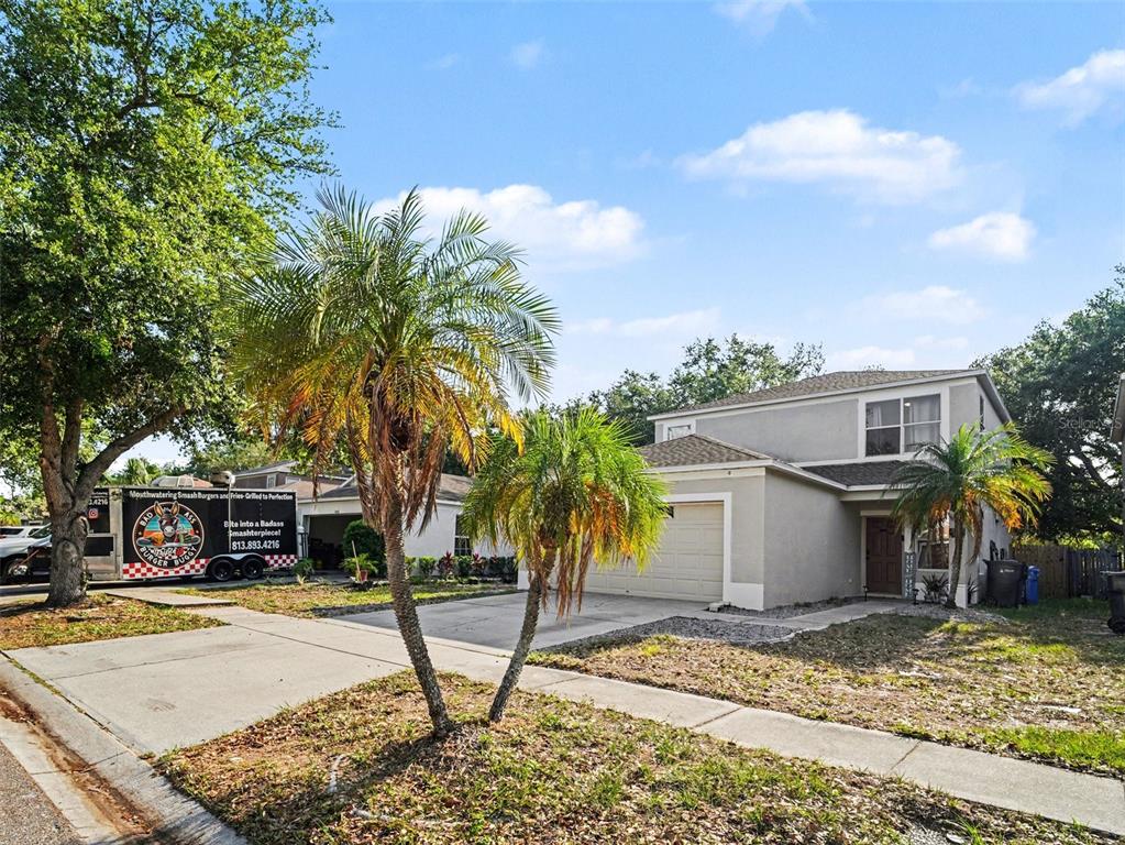 A two-story suburban house with a concrete driveway, palm trees, and a food truck parked nearby — 8430 QUARTER HORSE DRIVE, RIVERVIEW, FL
