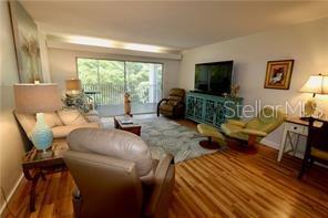 A living room features hardwood floors, a television on a blue console, and sliding glass doors — 3835 ALMERIA AVENUE UNIT C3, SARASOTA, FL