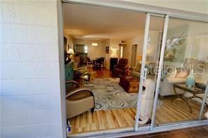 A view from a patio looking through sliding glass doors into a furnished living room — 3835 ALMERIA AVENUE UNIT C3, SARASOTA, FL