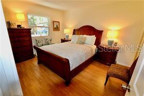 A bedroom features a wooden bed frame, two nightstands, a dresser, and light wood flooring — 3835 ALMERIA AVENUE UNIT C3, SARASOTA, FL