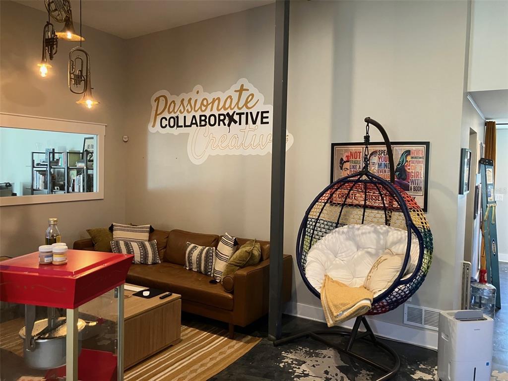 A living room features a brown leather sofa, a hanging egg chair, and wall lettering — 6401 N NEBRASKA AVENUE, TAMPA, FL