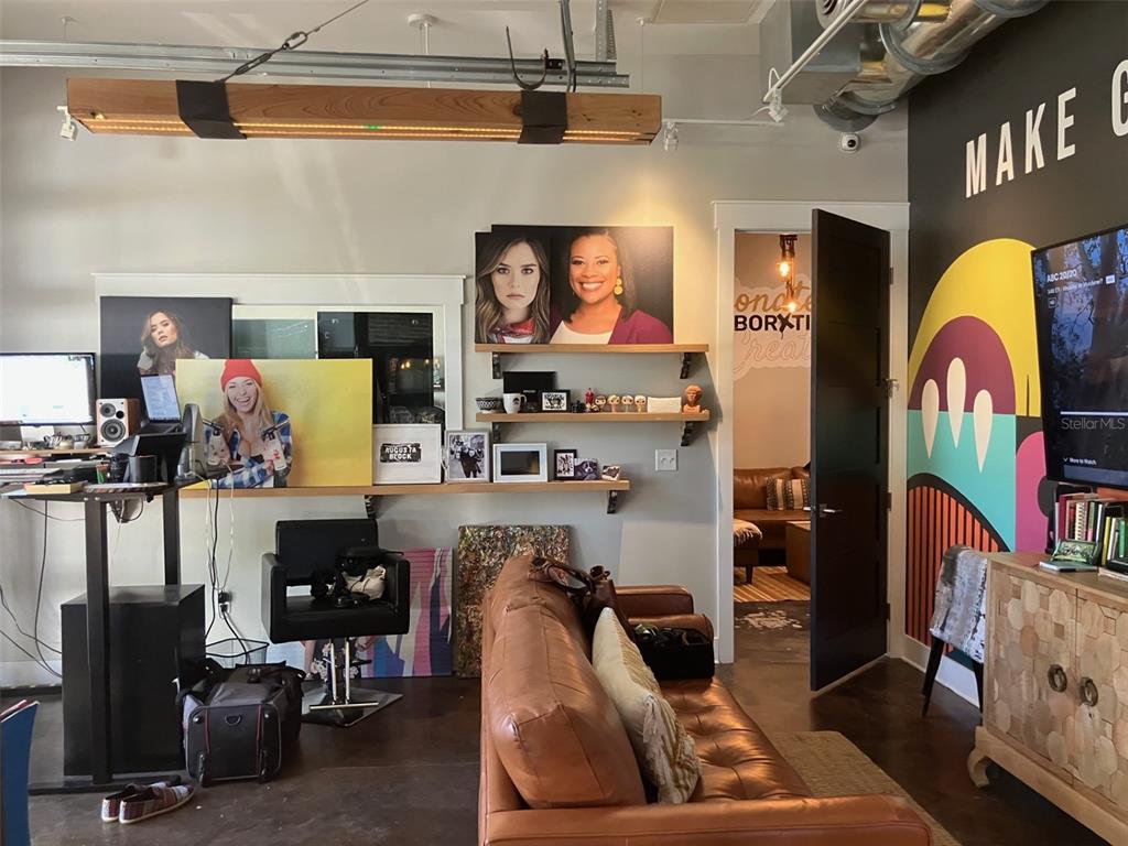 A modern office space features a brown leather sofa, wall art, shelving, and a television — 6401 N NEBRASKA AVENUE, TAMPA, FL