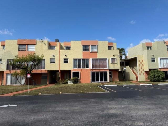 A multi-story apartment complex features tan and orange stucco walls under a clear blue sky — 9390 W Flagler St # 206C, Miami FL 33174, MIAMI, FL