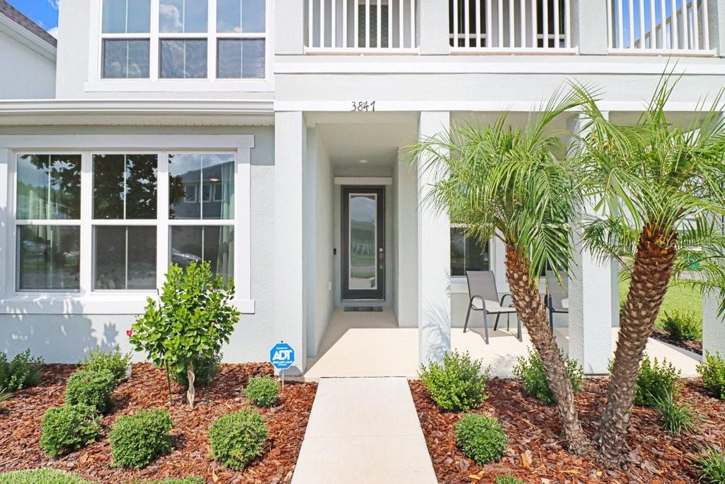 The exterior of a two-story home features a covered entryway, a walkway, and landscaping — 3847 LAJUANA BOULEVARD, WESLEY CHAPEL, FL