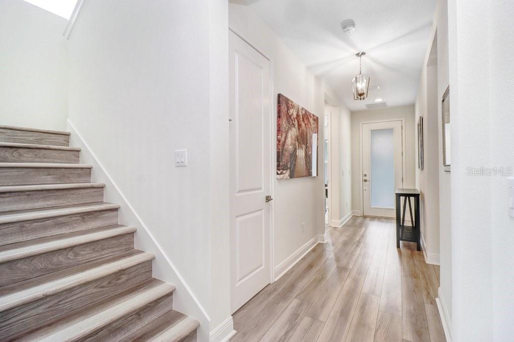 A bright entryway features light wood-look flooring, a staircase, and a white door — 3847 LAJUANA BOULEVARD, WESLEY CHAPEL, FL