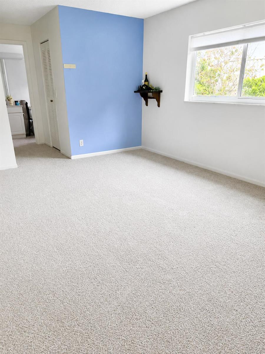 A room with beige carpet, white walls, and a blue accent wall with a small shelf — 14582 Sunny Waters Lane, Delray Beach FL 33484, DELRAY BEACH, FL