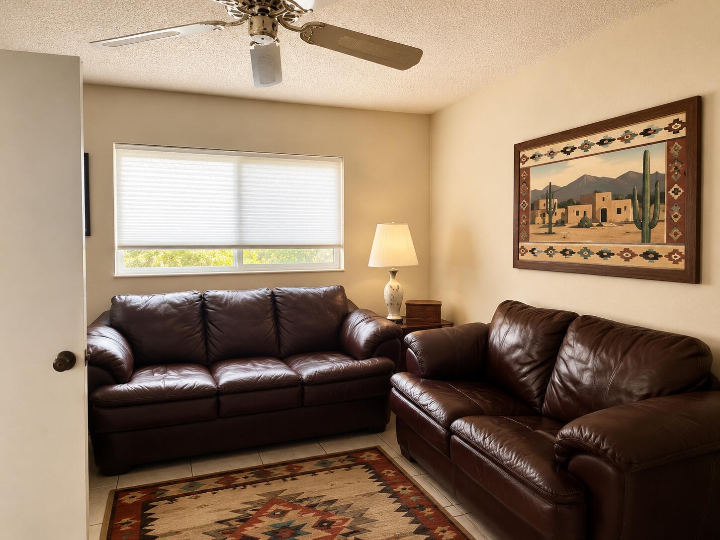 A living room features two brown leather sofas, a patterned area rug, and wall art — 14582 Sunny Waters Lane, Delray Beach FL 33484, DELRAY BEACH, FL