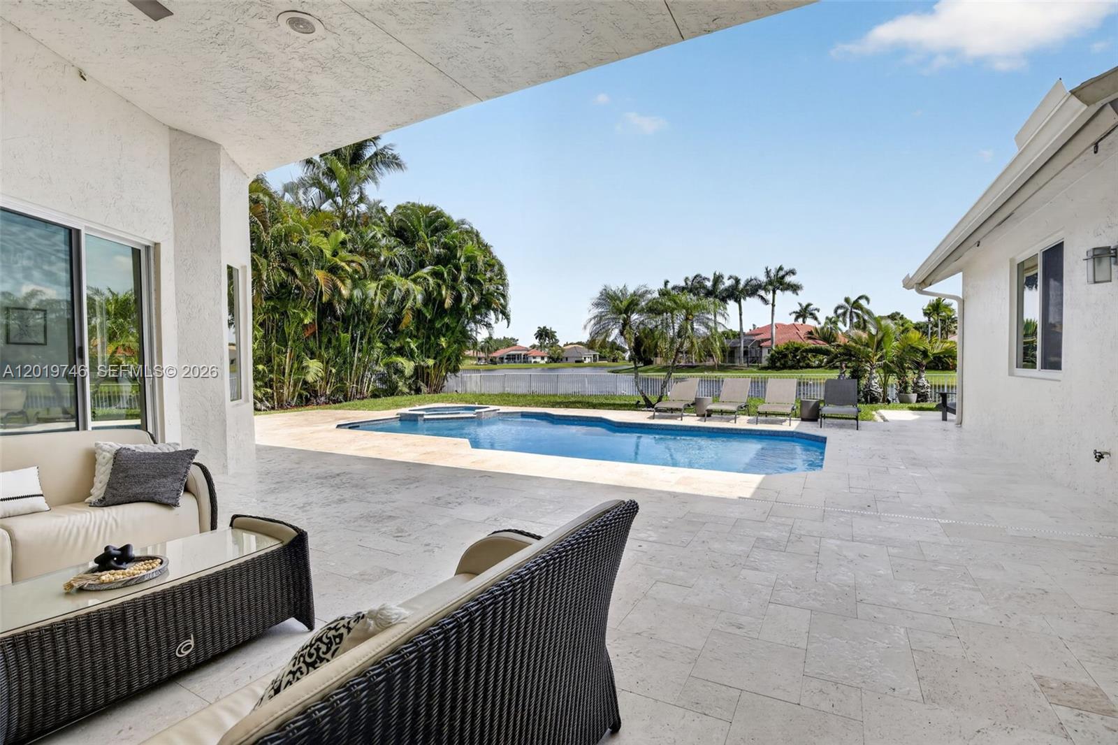 A covered patio overlooks a swimming pool and a lake in a residential backyard — 2922 Medinah, Weston FL 33332, WESTON, FL