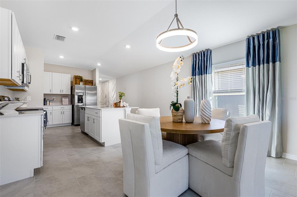 A dining area with a round table and upholstered chairs sits beside a white kitchen — 13210 TURNLEAF BOULEVARD, PUNTA GORDA, FL