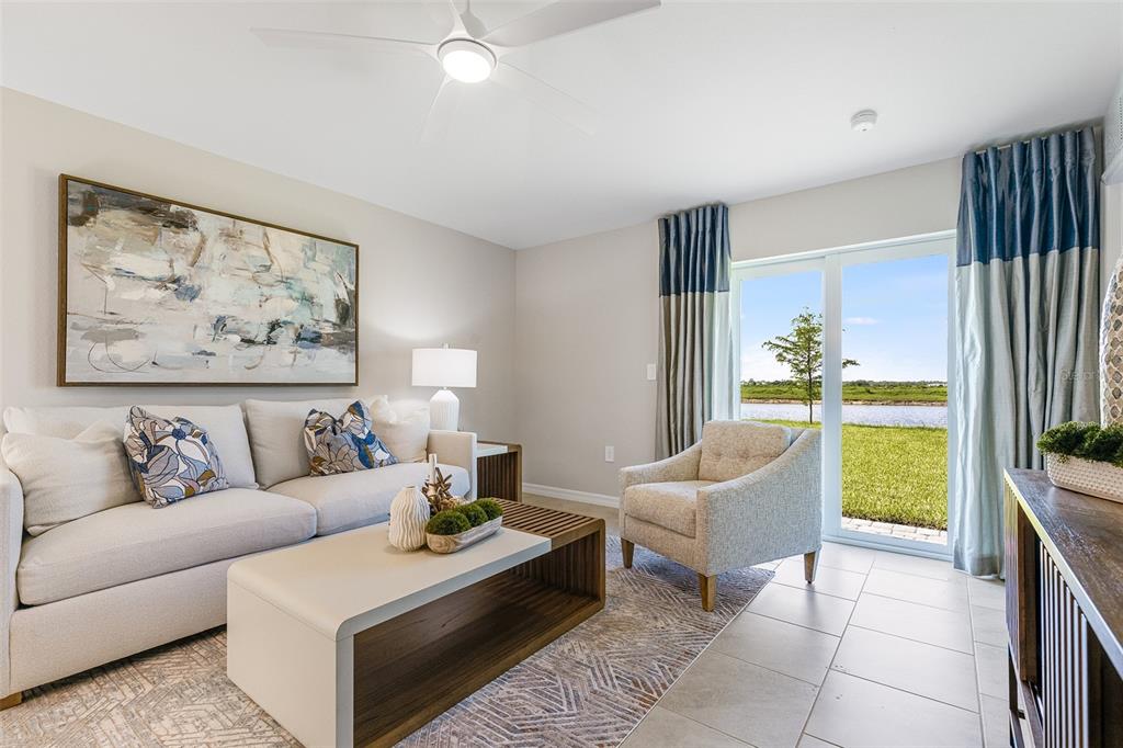 A living room features a sofa, armchair, coffee table, and sliding glass doors to water — 13210 TURNLEAF BOULEVARD, PUNTA GORDA, FL