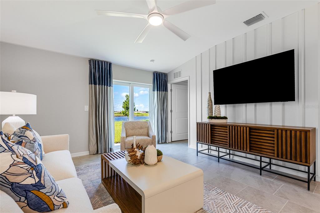 A living room features a wall-mounted television, a wooden media console, and a sliding door — 13210 TURNLEAF BOULEVARD, PUNTA GORDA, FL
