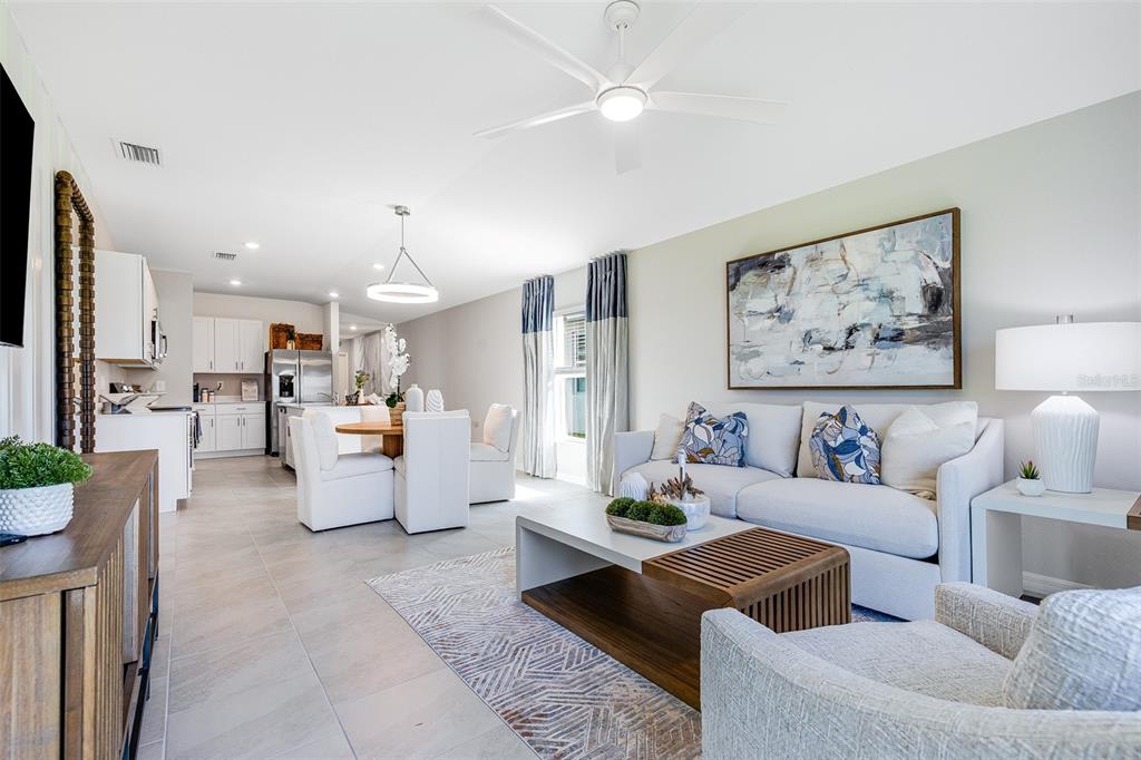 A bright open-concept living room features a white sofa, dining area, and modern kitchen — 13210 TURNLEAF BOULEVARD, PUNTA GORDA, FL