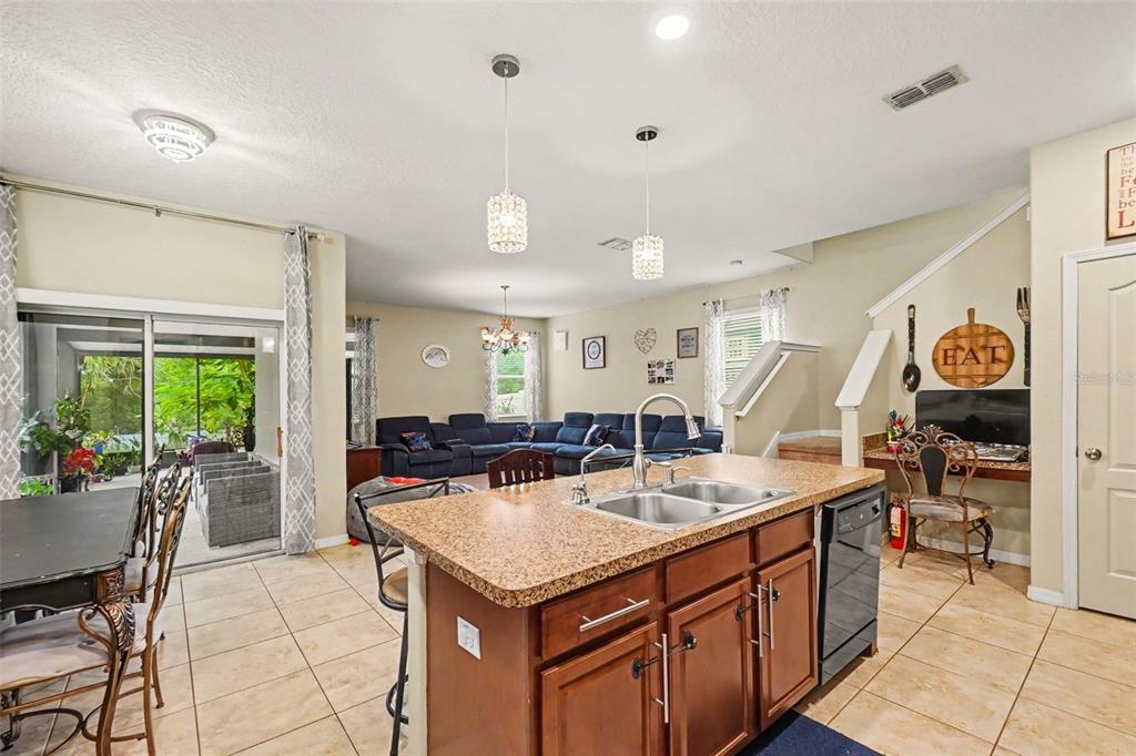 A kitchen island with a granite countertop sits in front of an open-concept living area — 11334 VILLAS ON THE GREEN DR, RIVERVIEW, FL